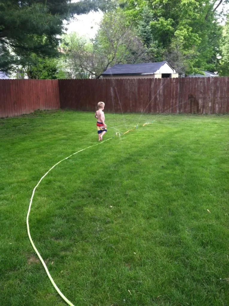 son playing in the sprinkler