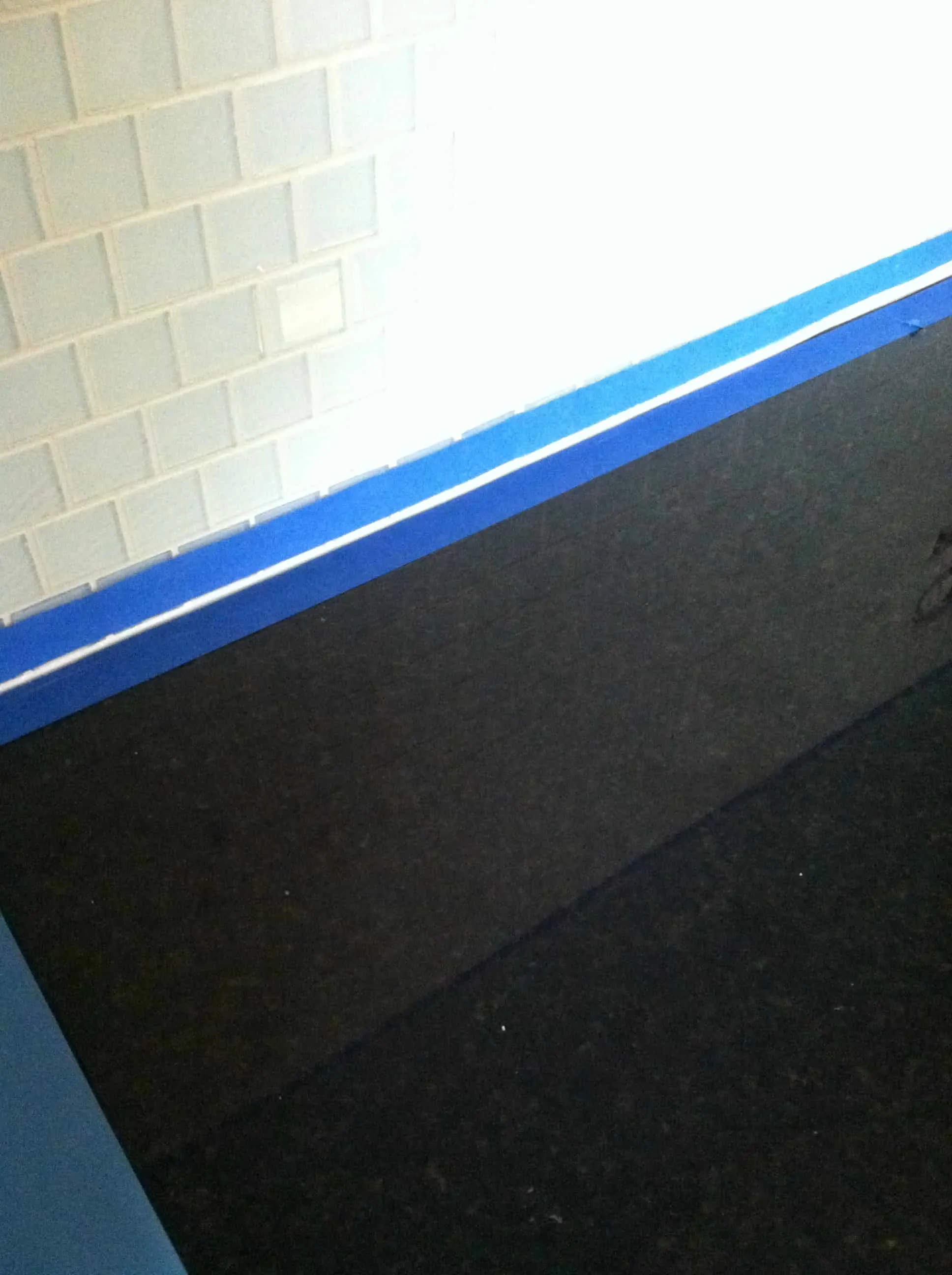taping off the edge between the counter top and wall for caulking