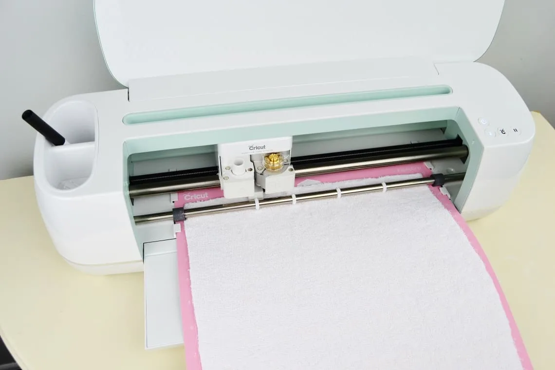 The Cricut Maker cutting out the bib pattern piece from terrycloth
