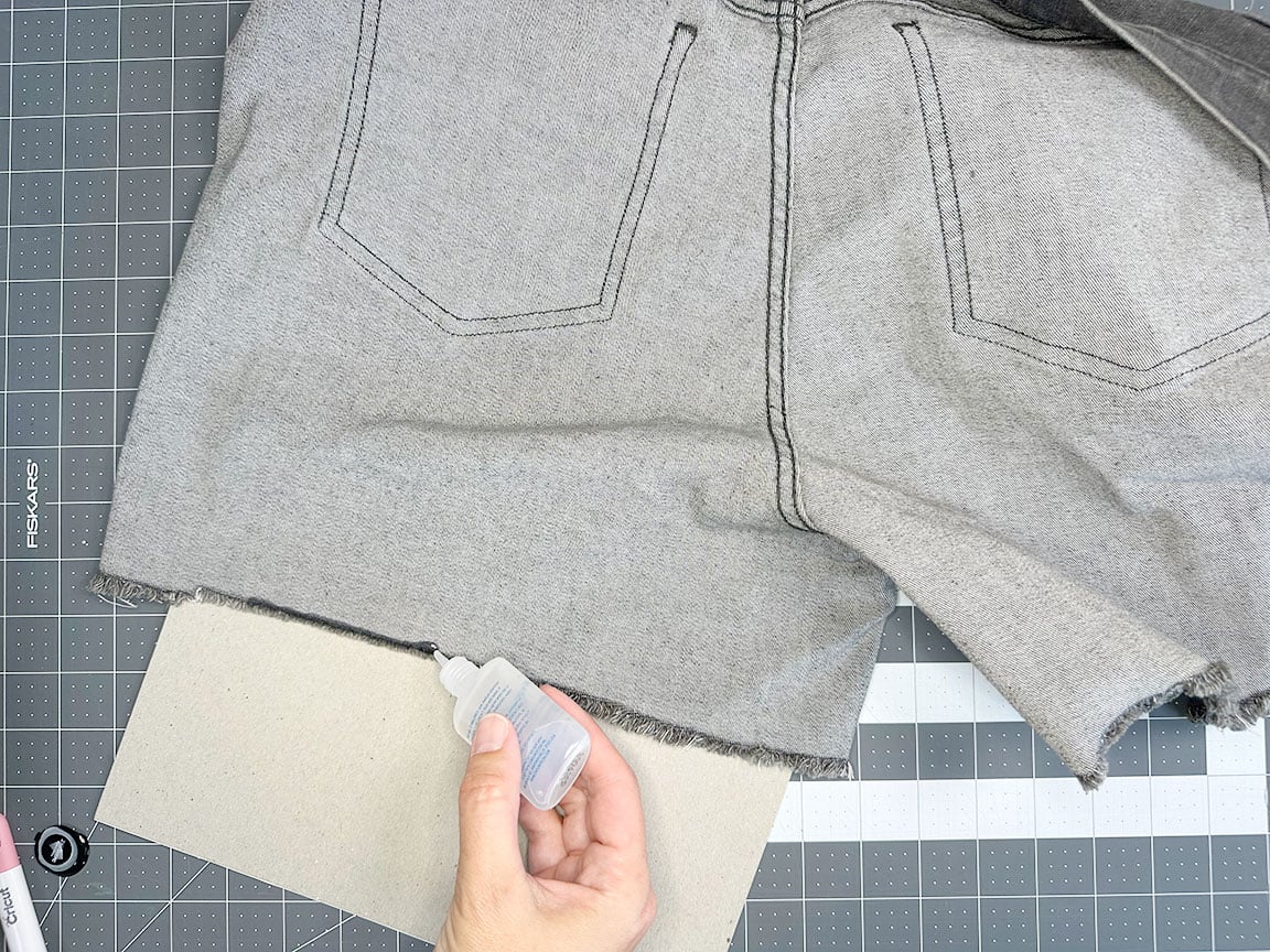 applying fray check to raw hem of jeans
