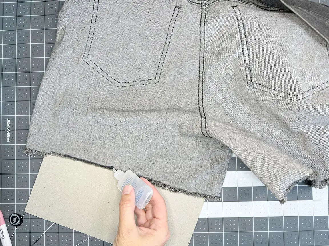 applying fray check to raw hem of jeans