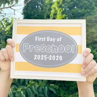 first day of school signs 2025 sign being held in front of bushes