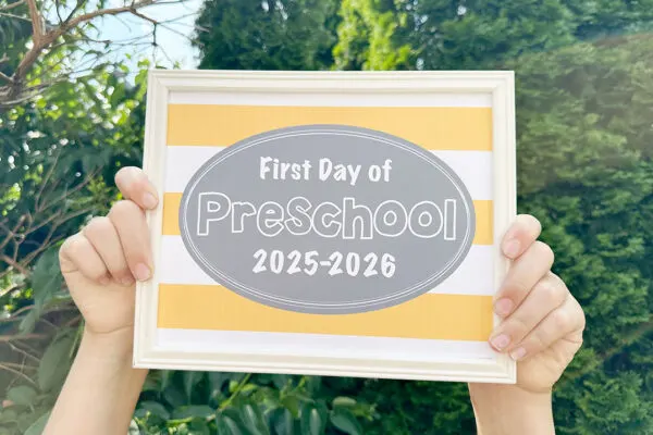 first day of school signs 2025 sign being held in front of bushes