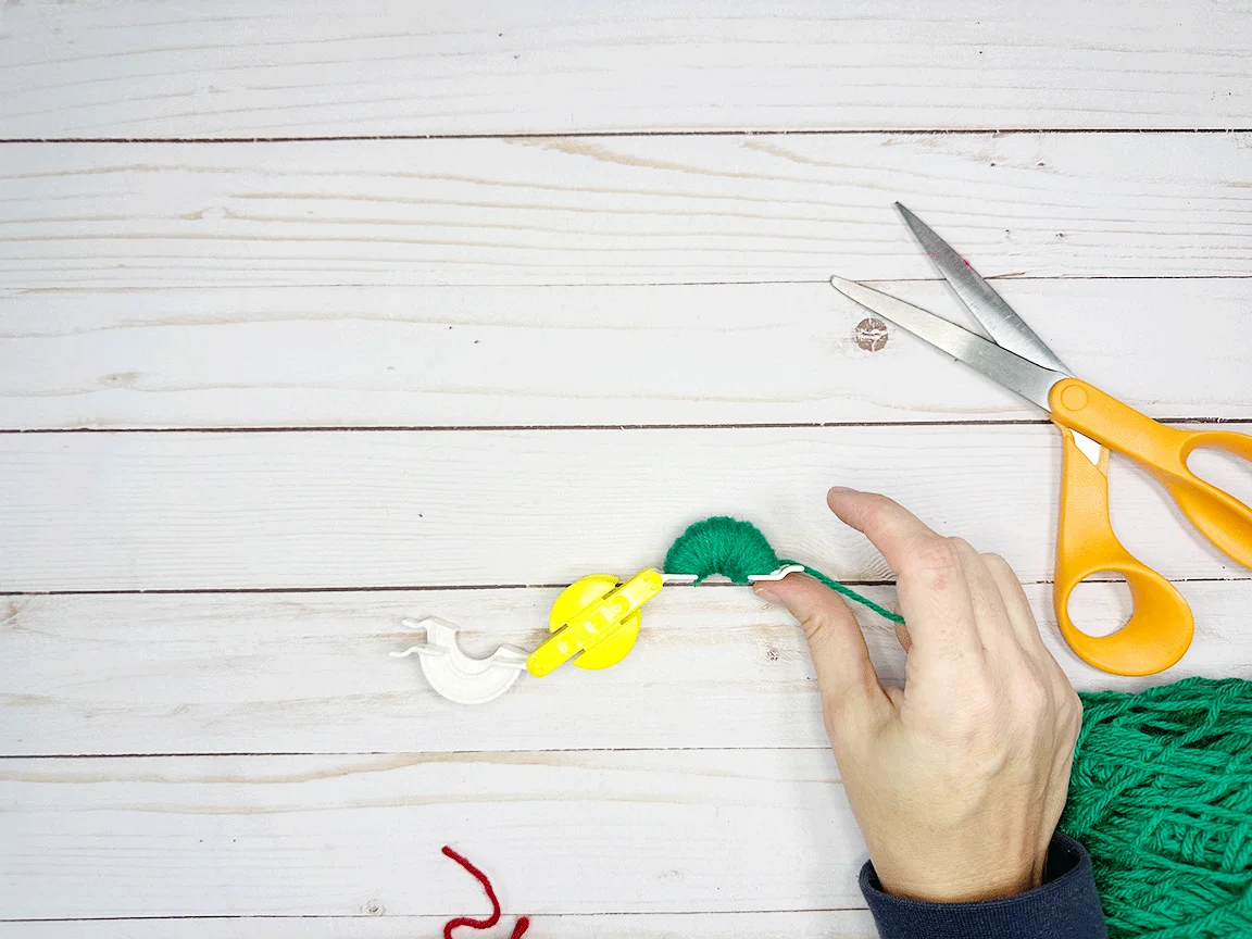 One side of the Pom Pom maker tool fully wrapped with yarn