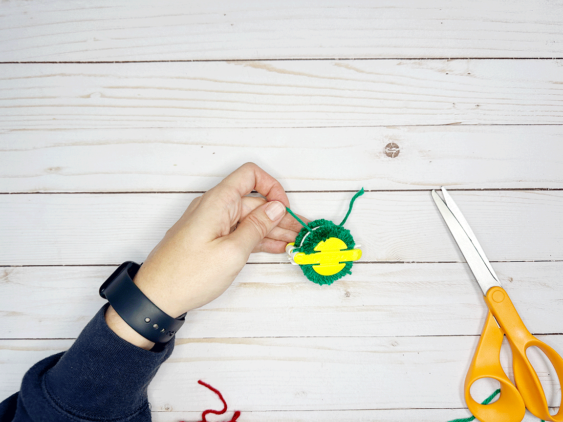 Tying a double knot in the Pom Pom to secure it