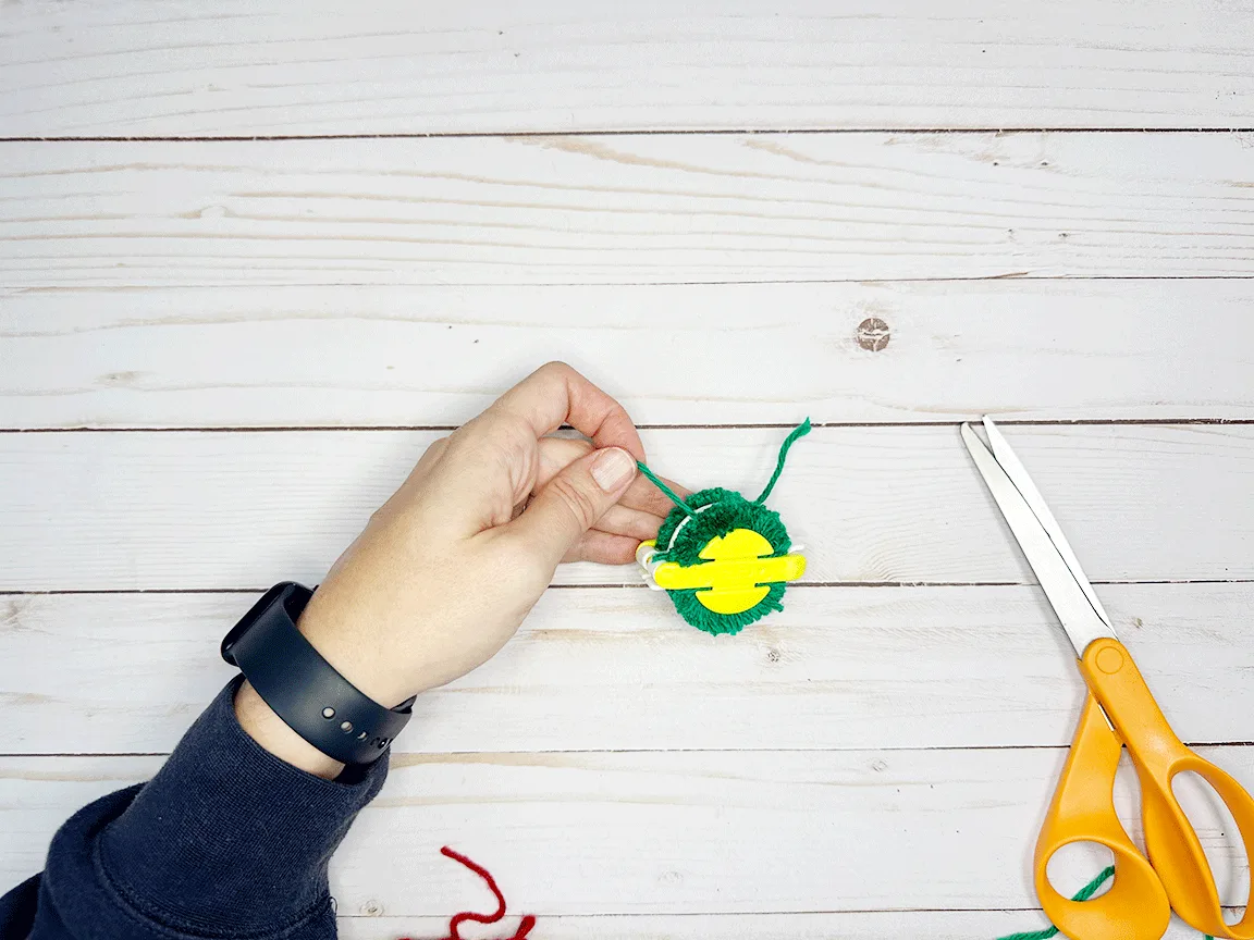 Tying a double knot in the Pom Pom to secure it